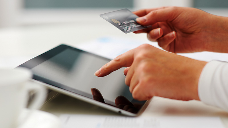 Person uses credit card to shop on tablet. 